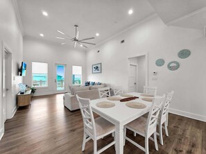 A modern living room with a white sofa, dining table with chairs, and a ceiling fan. - Salty Sunrise 4 Bedroom Home (Port Bolivar)