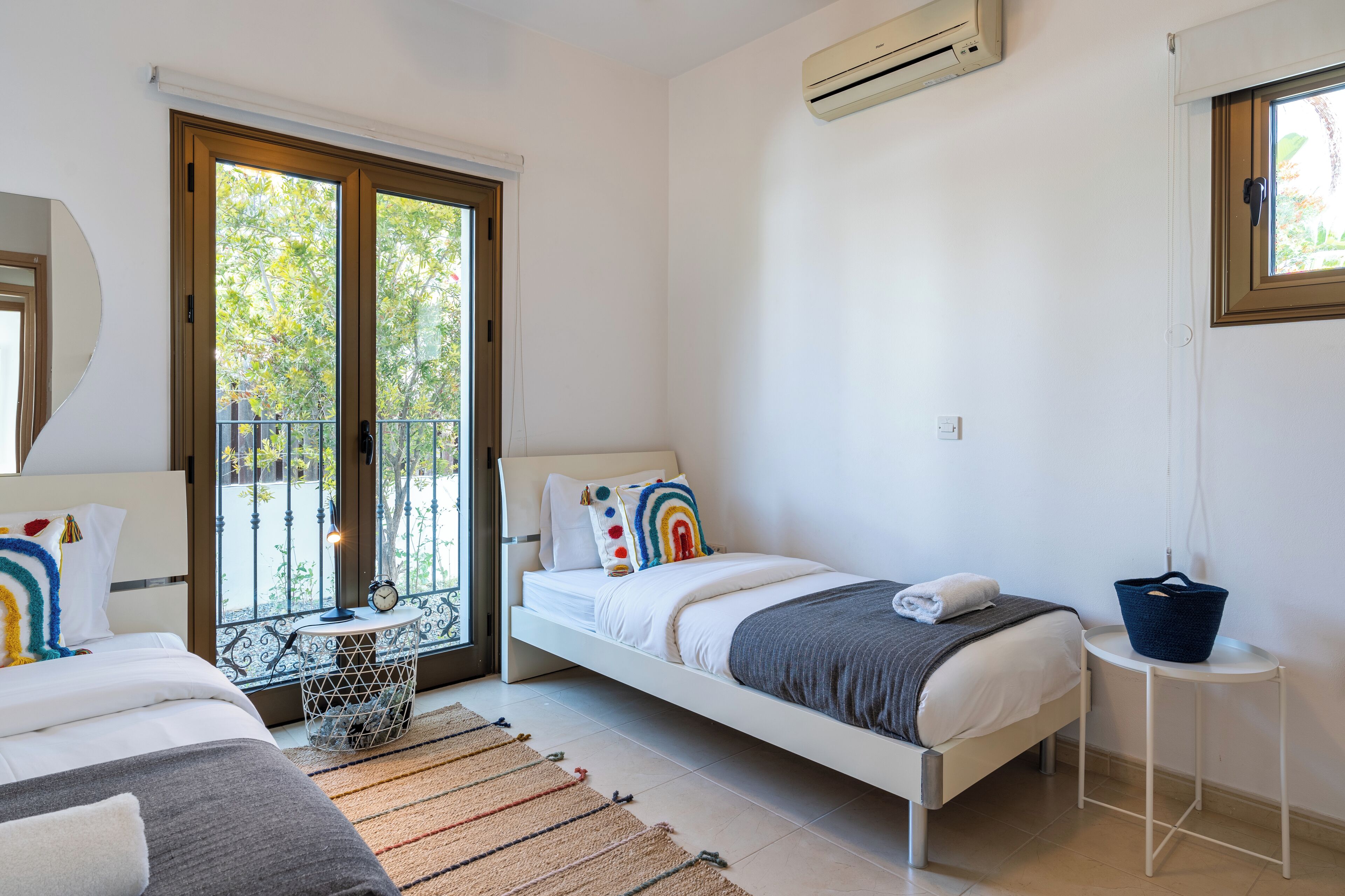A bedroom with a bed, a bedside table, a window, and an air conditioning unit.