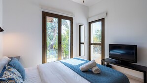 Une chambre d’hôtel moderne dotée d’un grand lit, d’une télévision à écran plat et d’un balcon avec des portes vitrées.