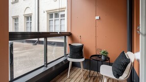 A balcony with a view of a street, a white chair with a black cushion, a small round table with a potted plant, and a black lamp. - Homelike 1BR Apt with Sauna & Balcony at Pyynikki (Tampere)