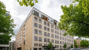 A multi-story building with a beige facade, large windows, and a flat roof. - Homelike 1BR Apt with Sauna & Balcony at Pyynikki (Tampere)