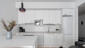 A modern kitchen with white cabinets, a built-in microwave, and a dishwasher. - Homelike 1BR Apt with Sauna & Balcony at Pyynikki (Tampere)