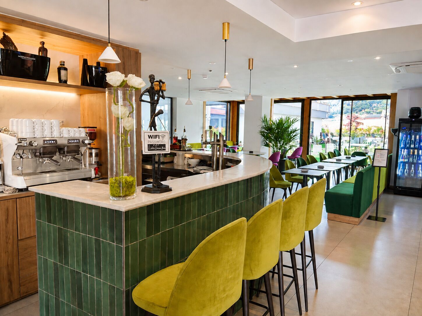 Un café moderne doté d’un bar, de coins salons et offrant une vue sur l’extérieur.
