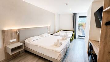 A hotel room with a large bed, bedside tables, a TV, and a view of the outdoors.