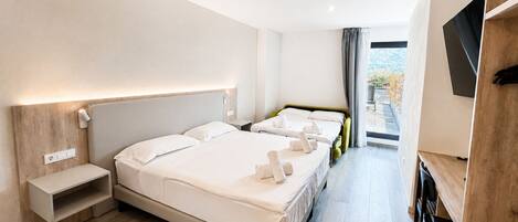 A hotel room with a large bed, bedside tables, a TV, and a view of the outdoors.