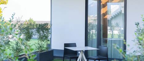 Une terrasse extérieure moderne, dotée d’une table et de chaises en verre, entourée de verdure et offrant une vue sur le paysage urbain.