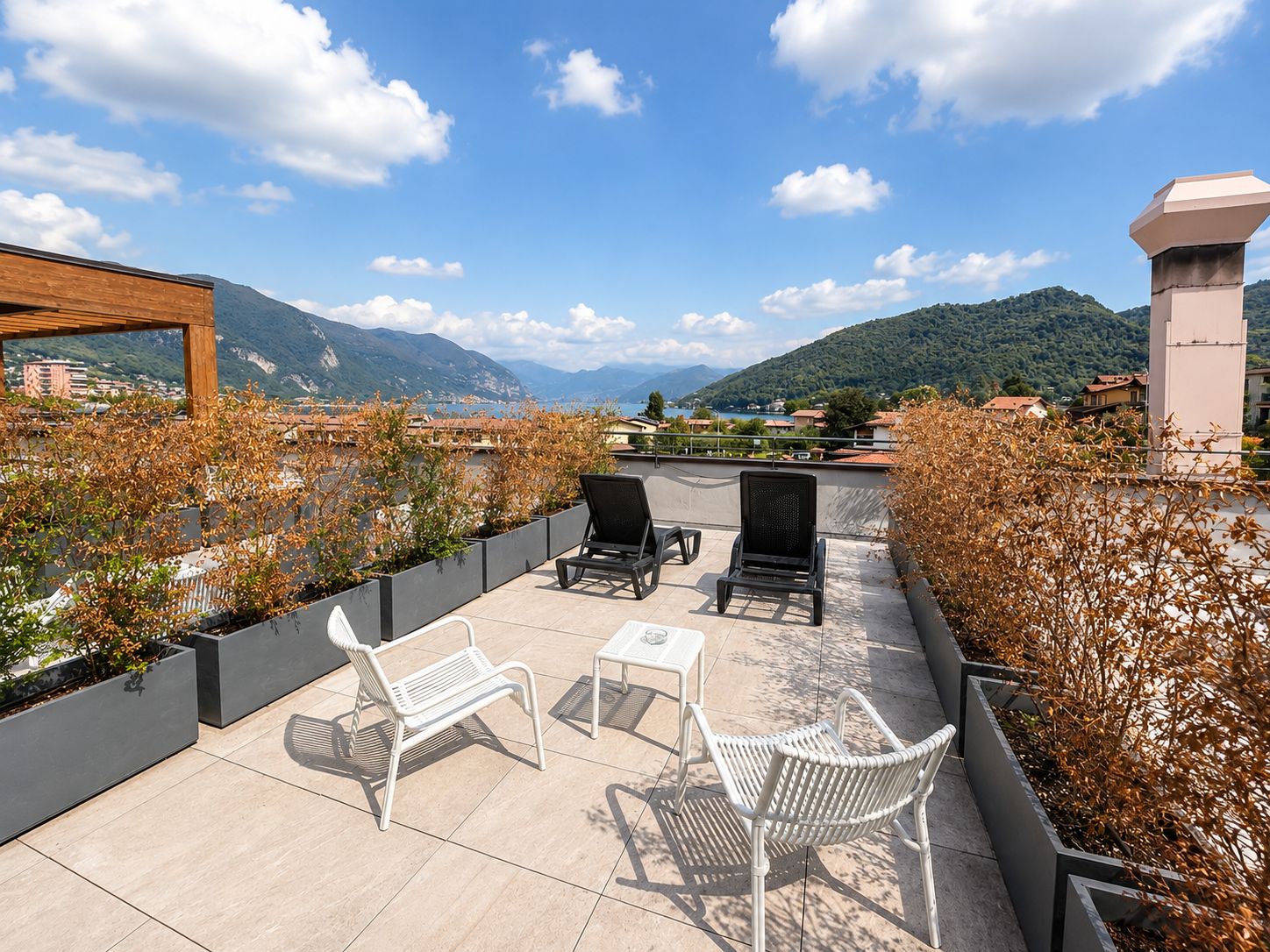 A terrace with outdoor furniture, a view of mountains, and a body of water in the background.