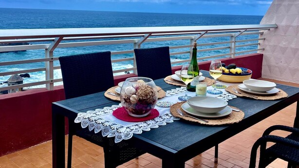 Una mesa dispuesta para comer con vista al océano.