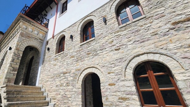 Un edificio de piedra con ventanas arqueadas y una escalera que conduce a un balcón.