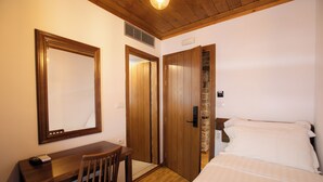 Un dormitorio con cama, escritorio, silla, espejo y puertas de madera.
