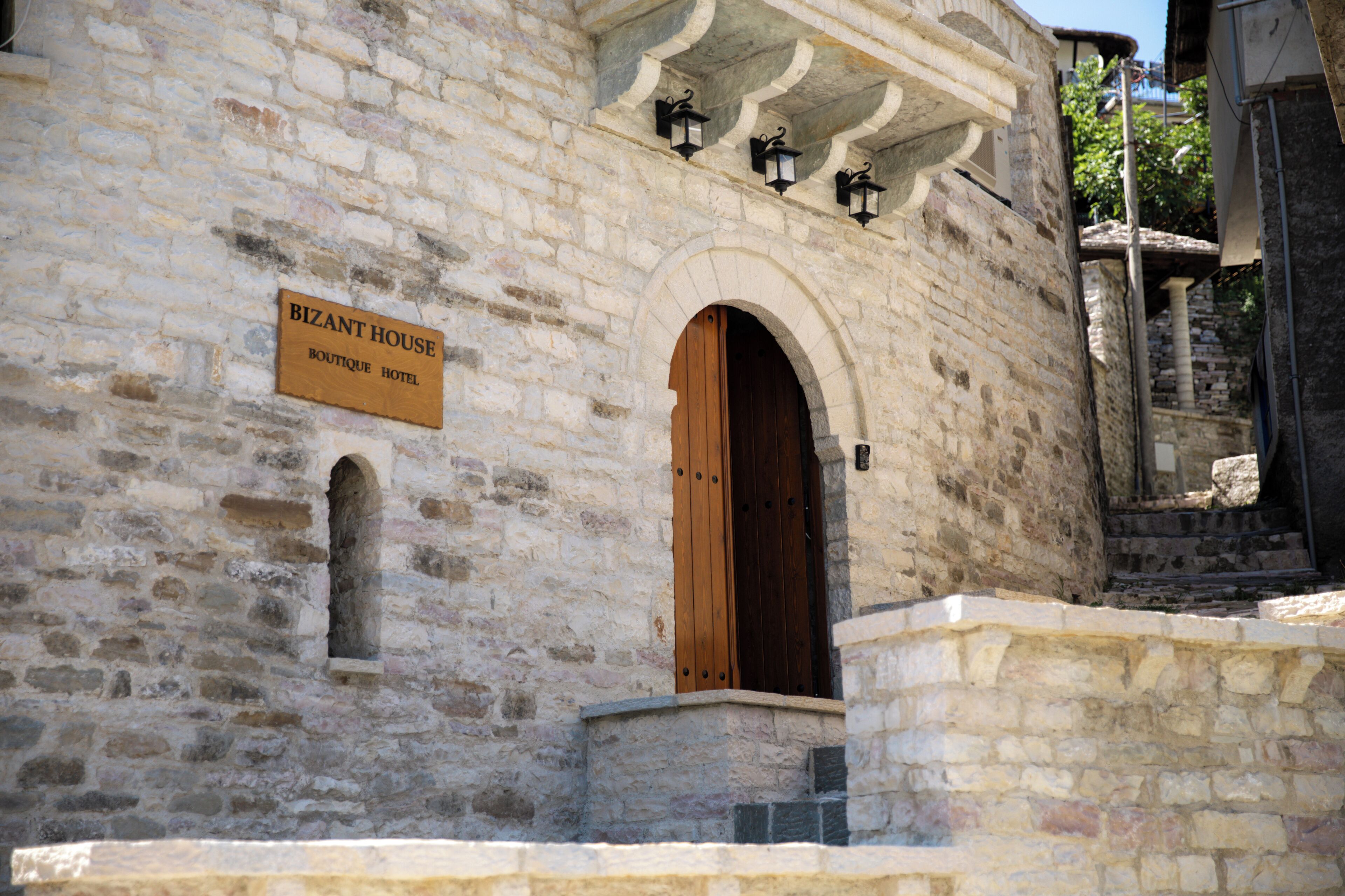 A stone building with a wooden door and a sign that reads 'BIZANT HOUSE BOUTIQUE HOTEL.'