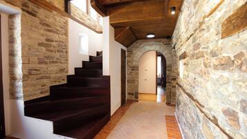 A staircase with stone walls and wooden beams, leading to an arched doorway.