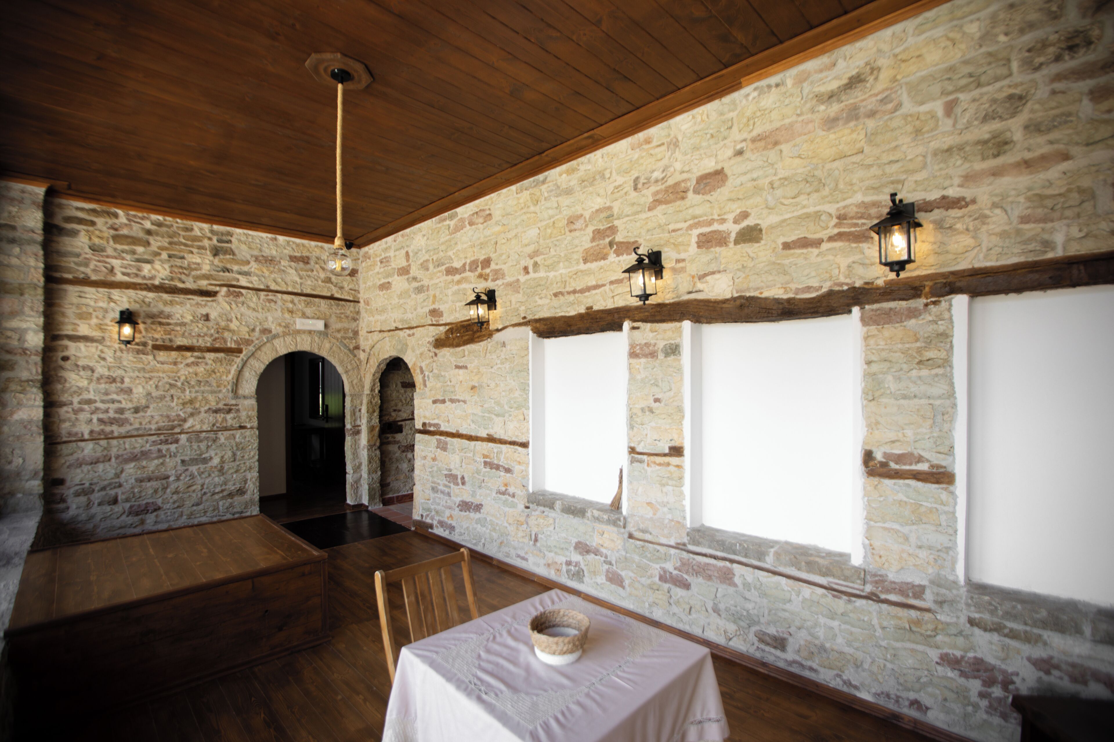 A room with stone walls, wooden beams, and a table with a white tablecloth.