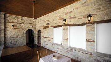 A room with stone walls, wooden beams, and a table with a white tablecloth.