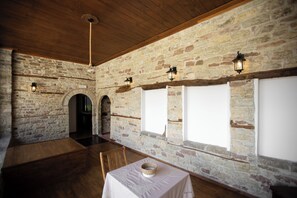 A room with stone walls, wooden beams, and a table with a white tablecloth. - Bizant House Boutique Hotel (Gjirokastër)