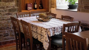 Una mesa de comedor con mantel de encaje, sillas de madera y una cesta de pan.