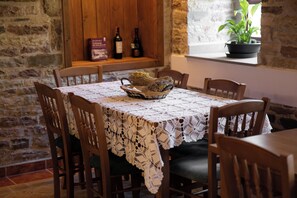 Una mesa de comedor con mantel de encaje, sillas de madera y una cesta de pan.