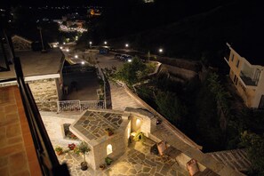 A stone staircase leading to a balcony with potted plants and a view of a street at night. - Bizant House Boutique Hotel (Gjirokastër)