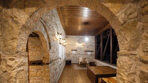 Un interior rústico de piedra con un banco de madera, una mesa y un comedor.