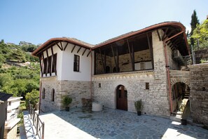A traditional stone building with a courtyard, featuring a stone staircase, wooden door, and potted plants. - Bizant House Boutique Hotel (Gjirokastër)