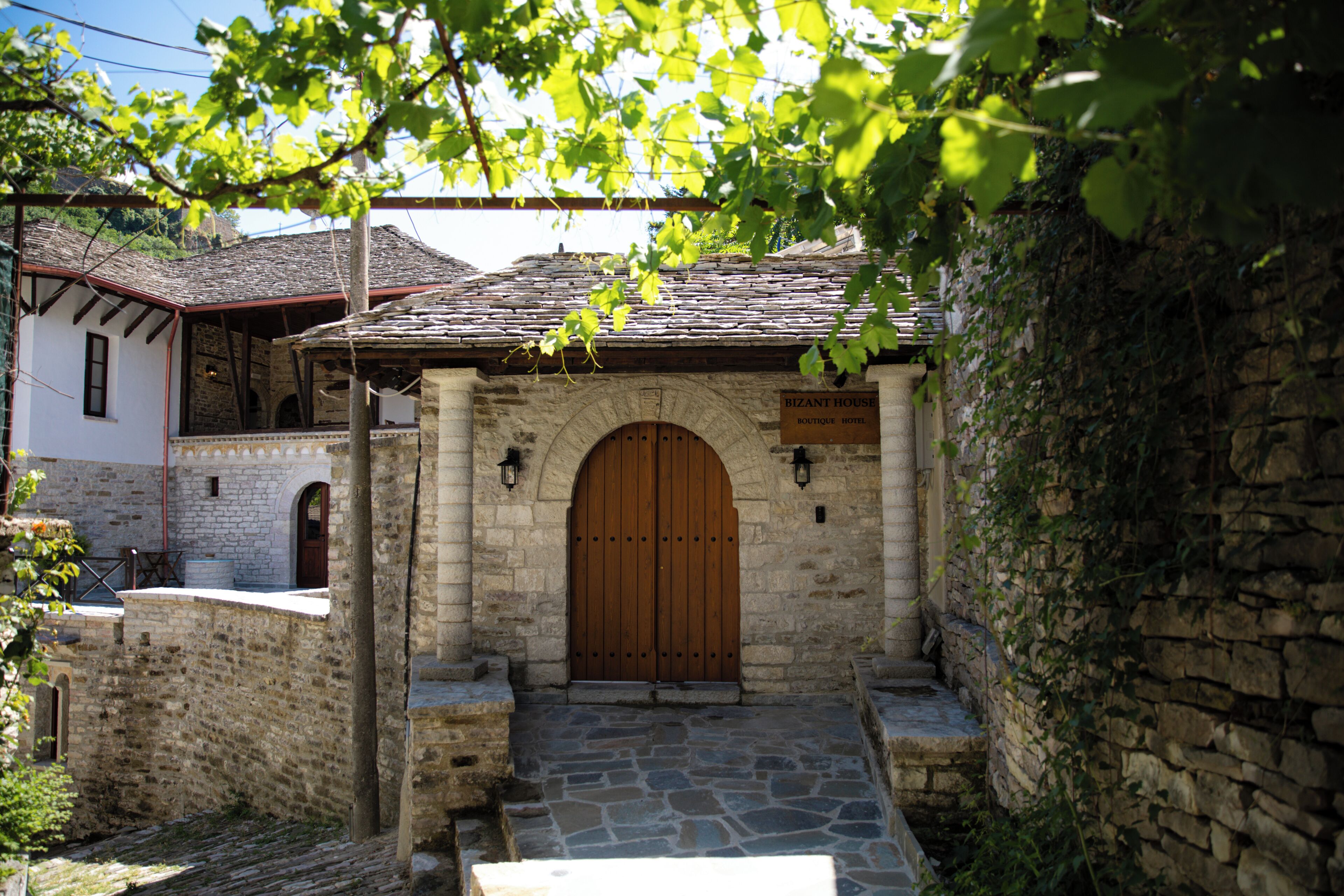 A stone building with a wooden door, a sign indicating it is a boutique hotel, and a stone staircase leading to the entrance.