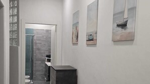 Un corridoio dal design moderno, con una parete d'accento scura, una reception e opere d'arte alle pareti.