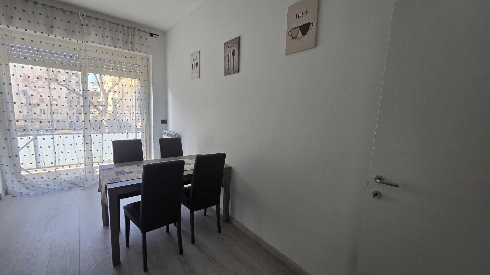 A dining area with a table and chairs, a window with a polka dot curtain, and wall decorations.