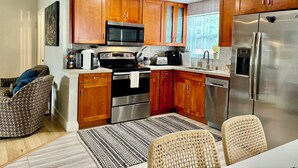 A modern kitchen with wooden cabinets, stainless steel appliances, and a dining area with wicker chairs. - Private Delray Beach Pool Home Near Atlantic Avenue, Dining & Beach (Delray Beach)