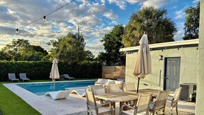 A poolside area with a table and chairs, a pool, and a covered patio. - Private Delray Beach Pool Home Near Atlantic Avenue, Dining & Beach (Delray Beach)