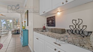 A modern kitchen with white cabinets, granite countertops, and a decorative metal piece.