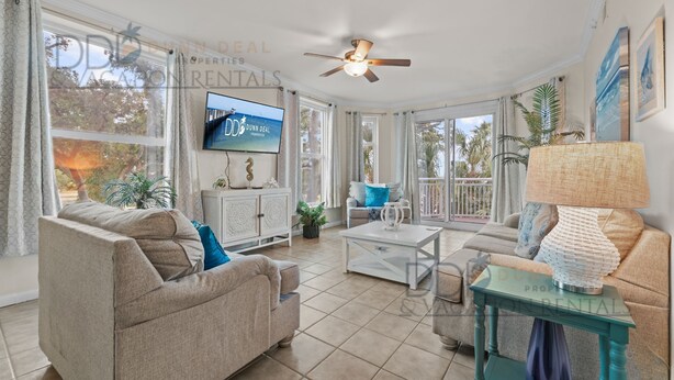 A spacious living room with a ceiling fan, a flat-screen TV, and a large window.