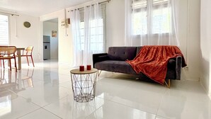 Amplia sala de estar con un sofá, una mesa redonda y una zona de comedor con sillas.