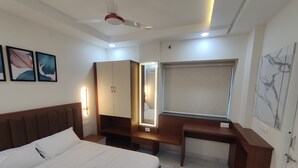 Une chambre d’hôtel équipée d’un lit, d’un bureau, d’une armoire et d’un ventilateur de plafond.