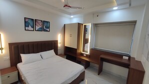 Une chambre moderne avec un grand lit, des tables de chevet, un bureau, une armoire et un ventilateur de plafond.