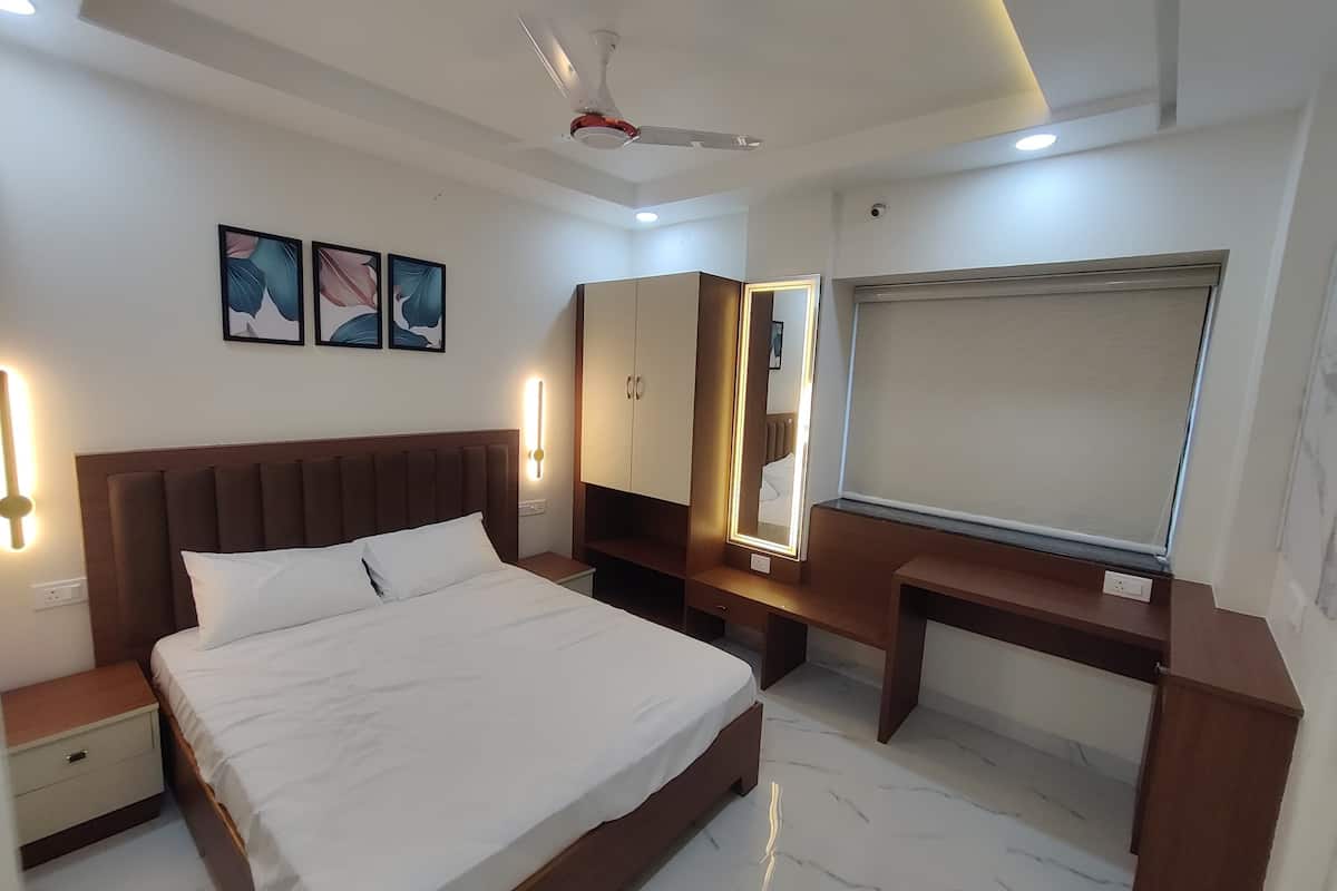 A modern bedroom with a large bed, bedside tables, a desk, a wardrobe, and a ceiling fan.