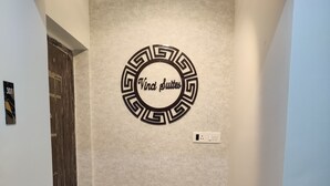 Un couloir doté d’un sol à motifs, une décoration murale circulaire portant l’inscription « Viva Suites », et une porte avec une plaque numérotée.