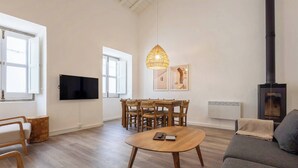 A modern living room with a dining area, a fireplace, and a television.