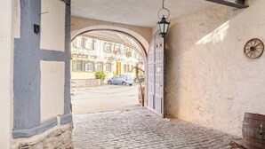 A cobblestone alleyway leading to a building with a large arched entrance. - Stilhaus 1730 - Central. Quiet. Unique. 1st floor (Königsbach-Stein)