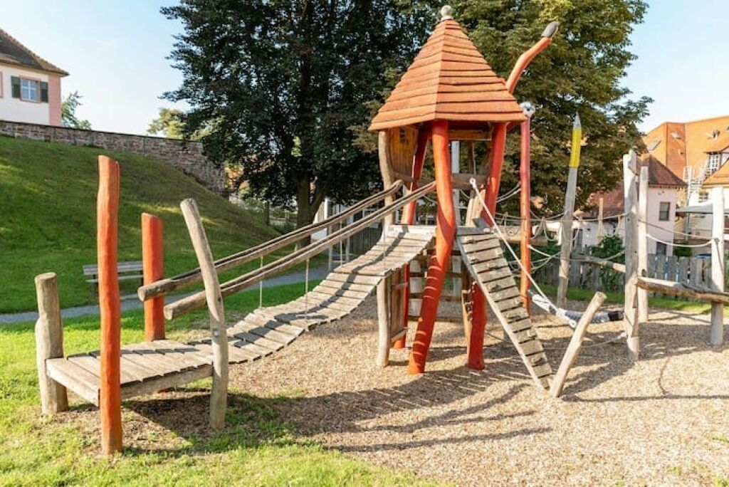 Une aire de jeux avec une structure d’escalade en bois et un toboggan.