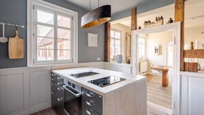 A modern kitchen with a central island, built-in appliances, and a large window providing natural light. - Stilhaus 1730 - Central. Quiet. Unique. 1st floor (Königsbach-Stein)