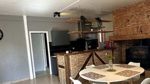 A modern kitchen with a brick wall, a wooden island, and a built-in stove. - Farm cottage (LALINDE)