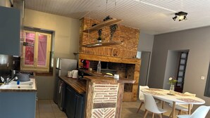 A modern kitchen with a central island, built-in appliances, and a brick accent wall. - Farm cottage (LALINDE)