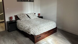 A bedroom with a bed, two bedside tables, a wall-mounted artwork with the word "LOVE", and a wooden floor. - Farm cottage (LALINDE)