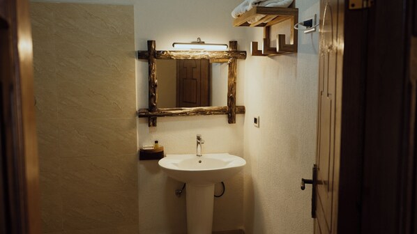 Un baño con un lavamanos blanco, un espejo con marco de madera y un perchero sobre el lavamanos.