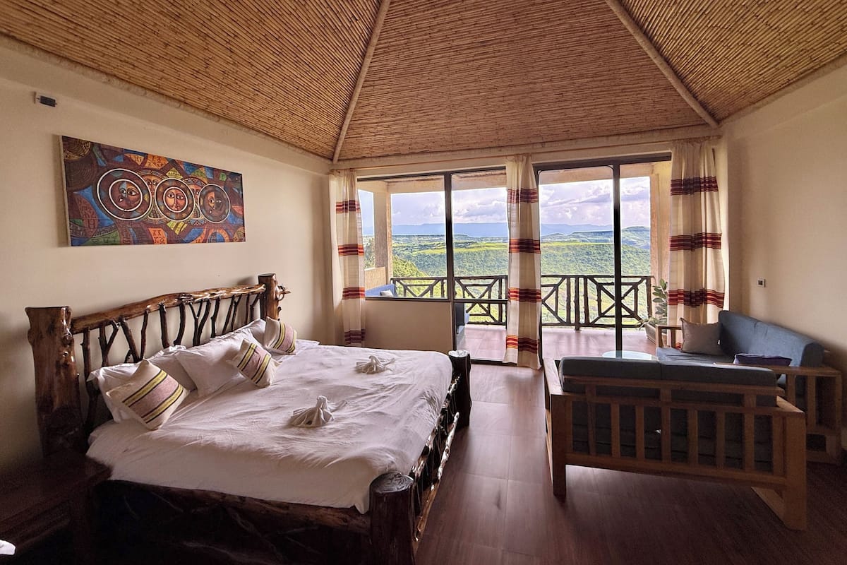 Un dormitorio con cama, cabecera de madera, un cuadro y balcón con vistas.