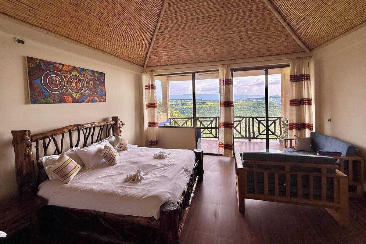 Un dormitorio con cama, cabecera de madera, un cuadro en la pared y un balcón con vistas.