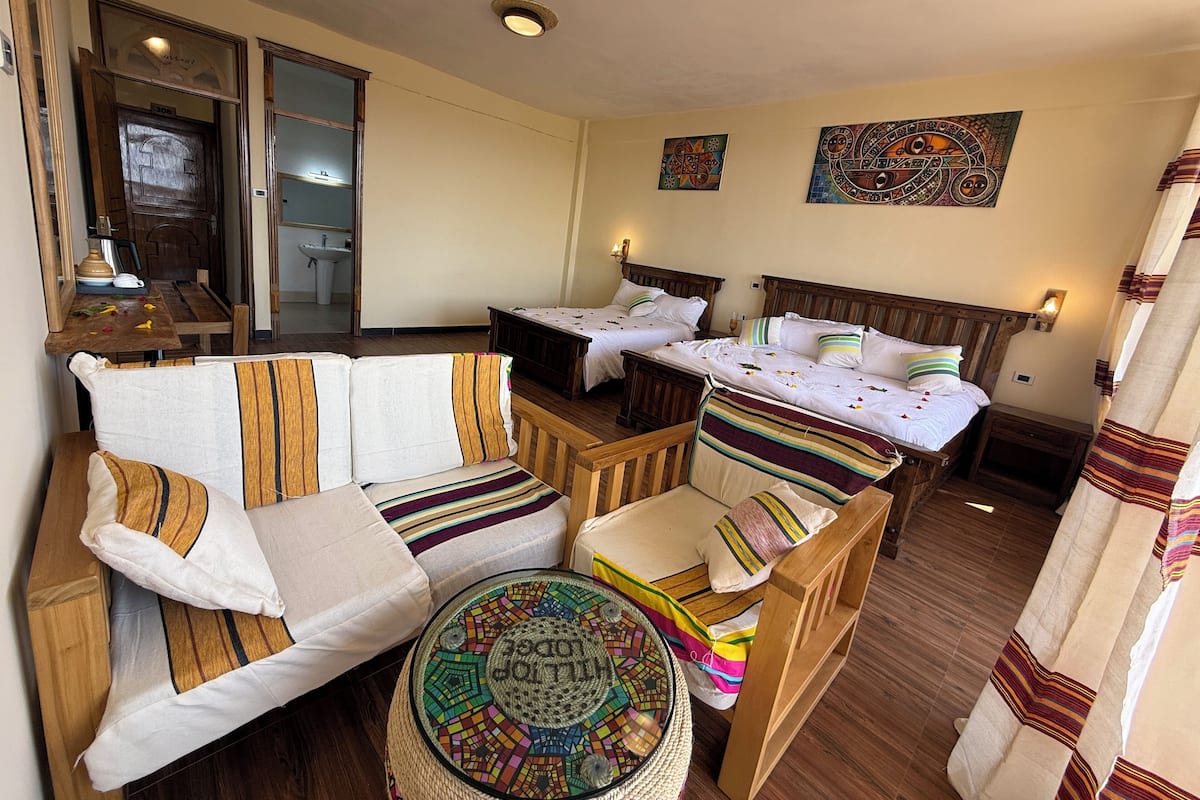 Una habitación acogedora con un sofá de madera, dos camas individuales, una mesita pequeña y una alfombra decorativa.