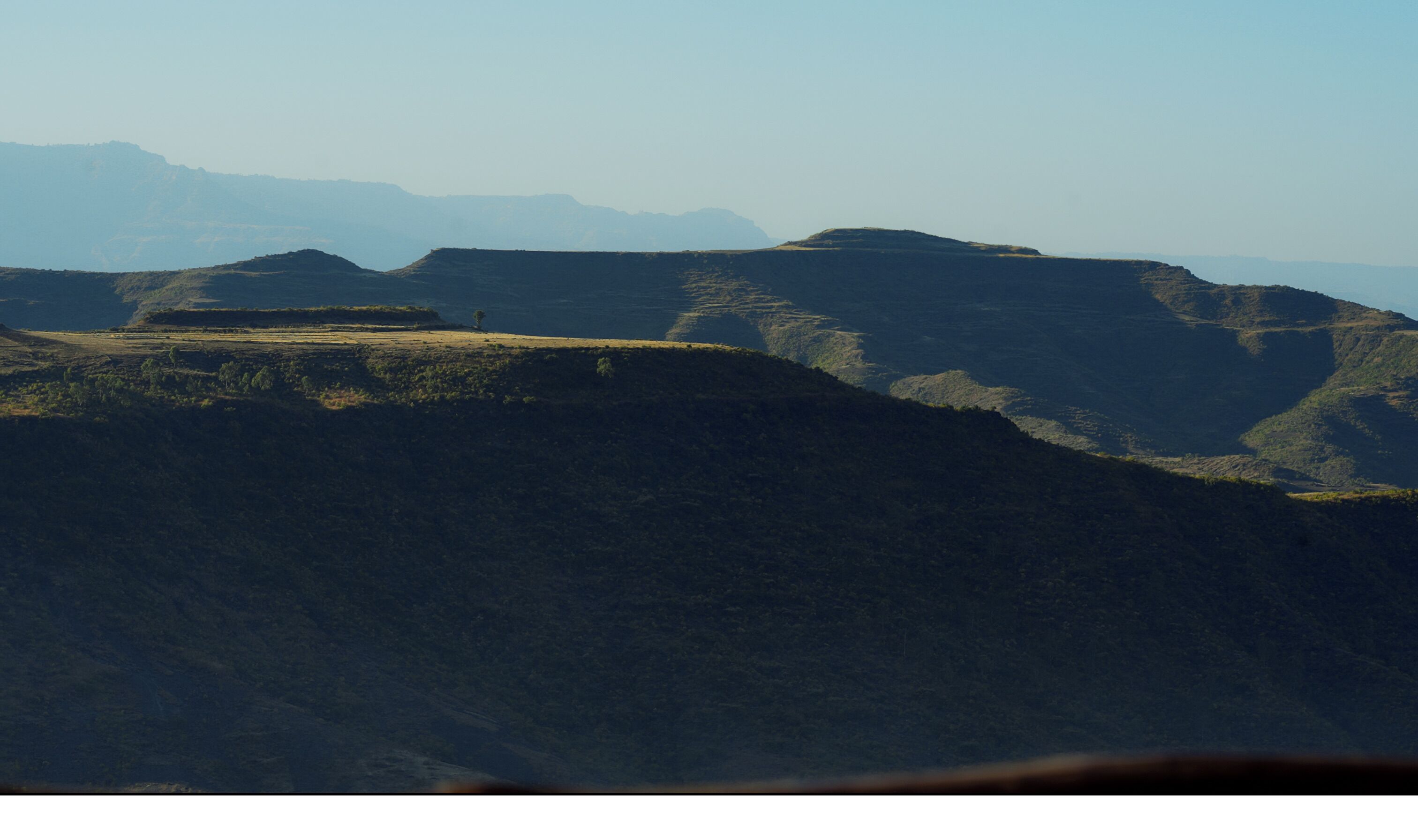 A mountainous landscape with rolling hills and sparse vegetation.