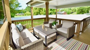 A covered outdoor seating area with wicker furniture and a striped rug.