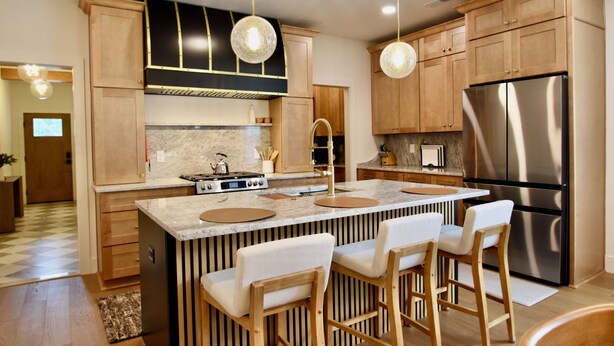 A modern kitchen with wooden cabinets, stainless steel appliances, and a central island with bar stools.